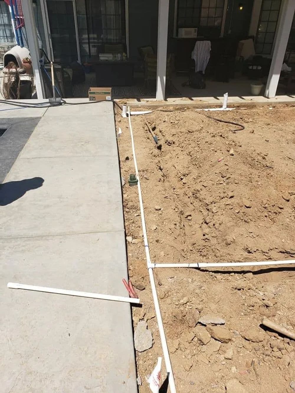 Construction site with laid out plumbing pipes and prepared ground for a new structure.