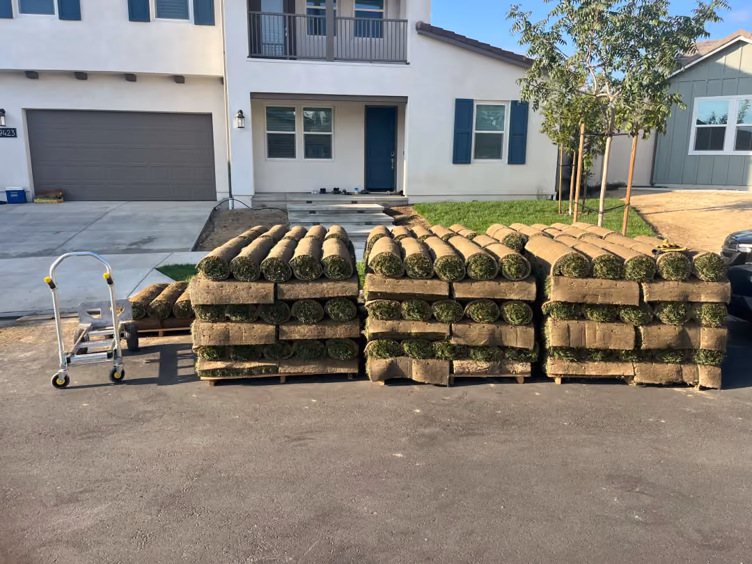A pile of freshly cut grass clippings in front of a residential house.