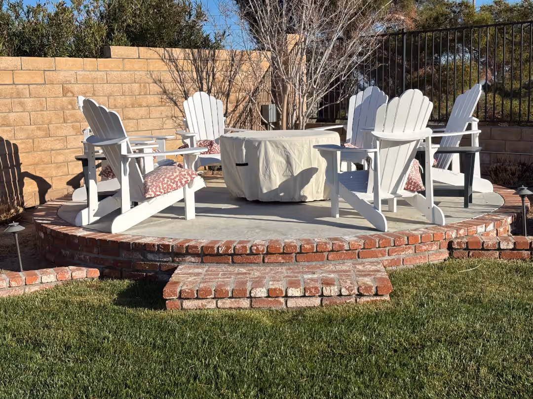 A brick patio featuring four chairs arranged around a central fire pit, creating a cozy outdoor gathering space.
