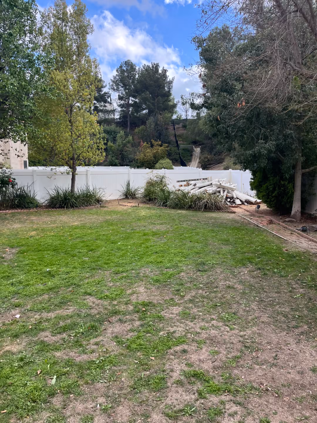 A backyard featuring a green lawn enclosed by a wooden fence, creating a private outdoor space.