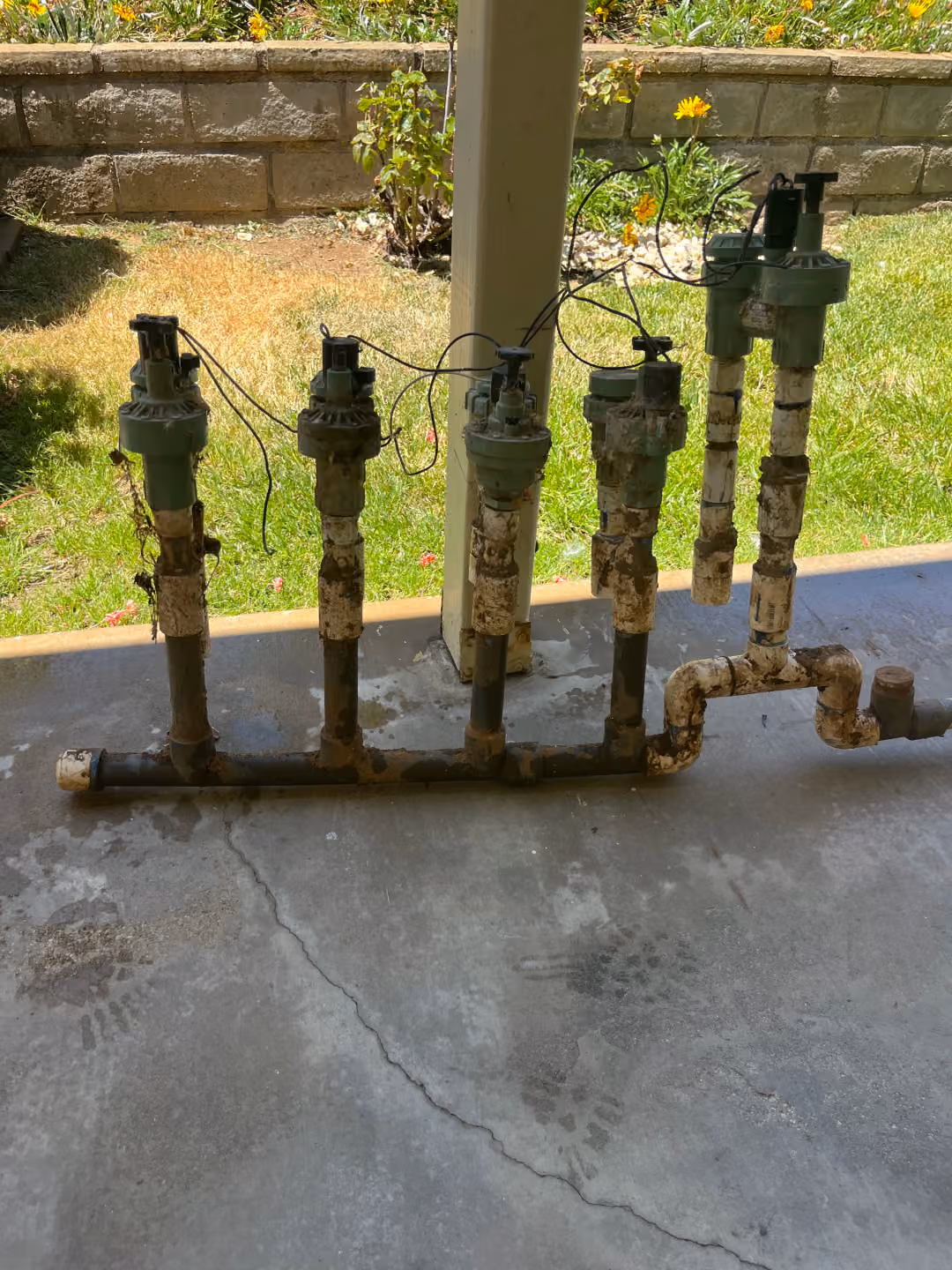 A cluster of industrial pipes and valves arranged on a concrete floor, showcasing their metallic structure and connections.