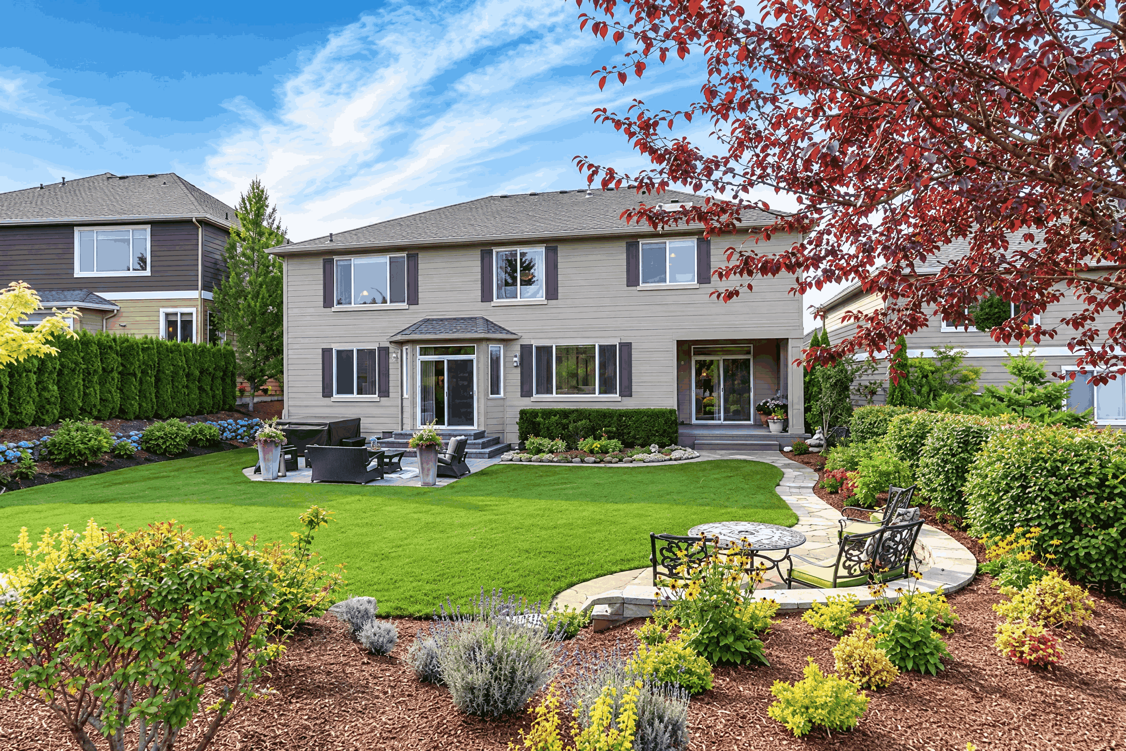 A picturesque yard showcasing a vibrant lawn and a variety of trees providing shade.